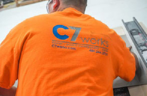 Man working with the C7 logo on the back of his shirt